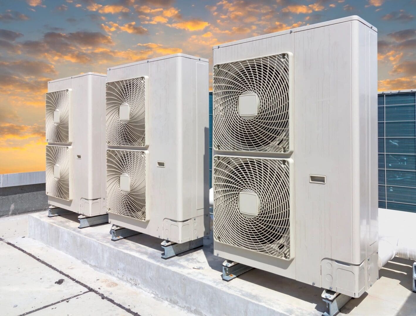 Outdoor air conditioning units lined up under a colorful sky.